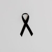 Black awareness ribbon symbolizing support and solidarity on a white background.